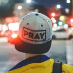 Kopf einer Person, die ein Cappy trägt mit der Aufschrift "pray"